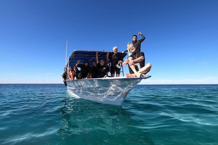 A boat with people on it floating on calm blue water. 4