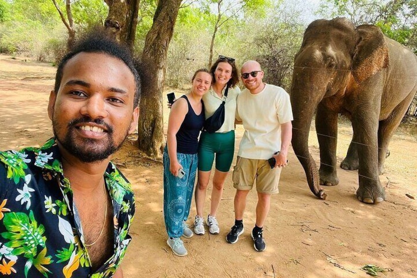 Un grupo de personas de pie sobre un sendero de tierra con un elefante al fondo. 1