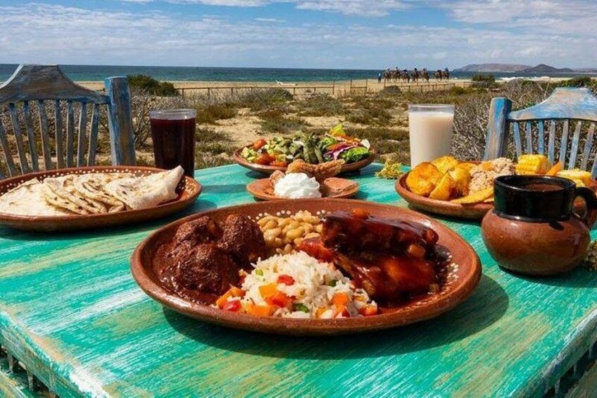 A table with various dishes, a beach in the background, and a clear sky. 3