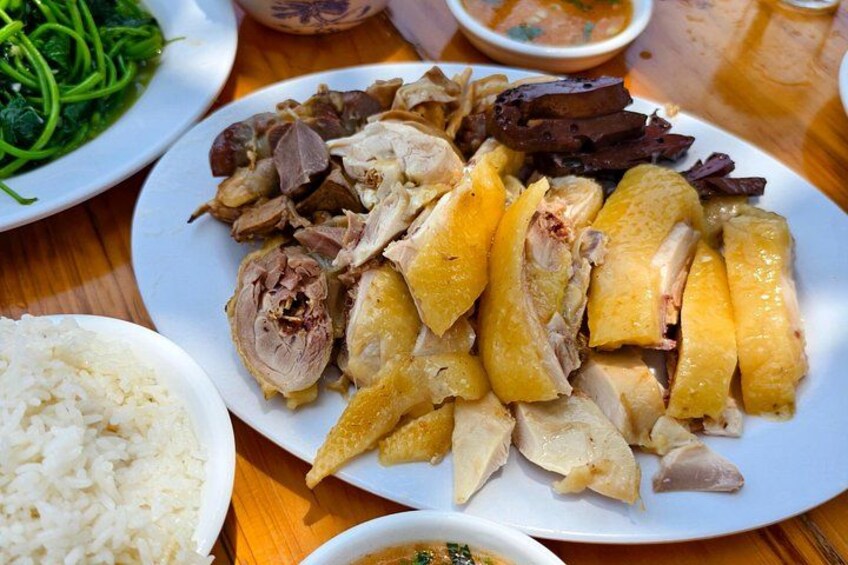 A plate of sliced chicken, rice, and vegetables on a wooden table. 3