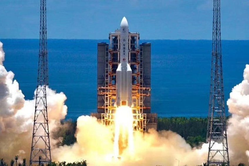 A rocket launch with a launch tower and ocean in the background. 1