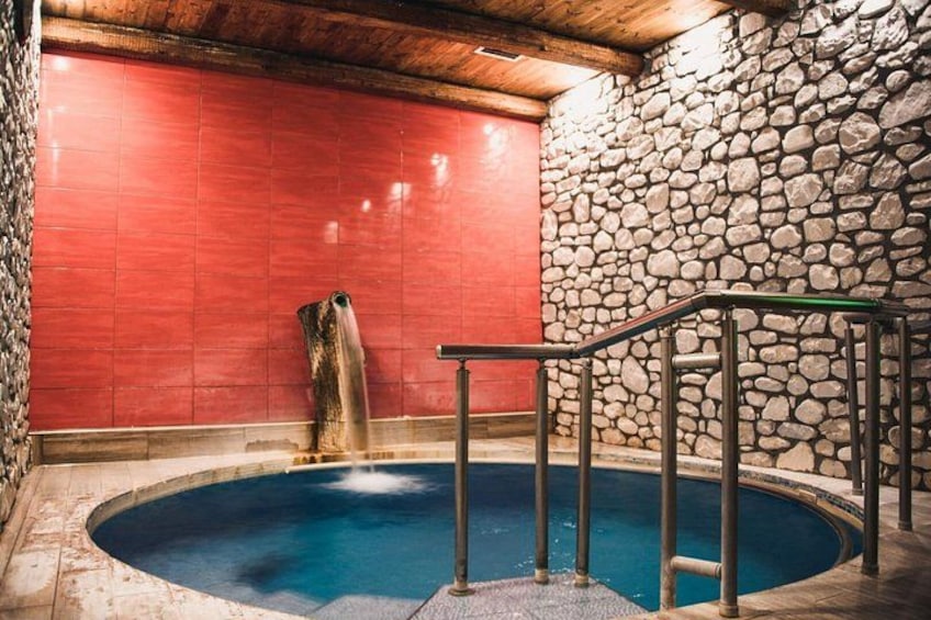 A hot tub with a stone wall and a red wall in the background. 2