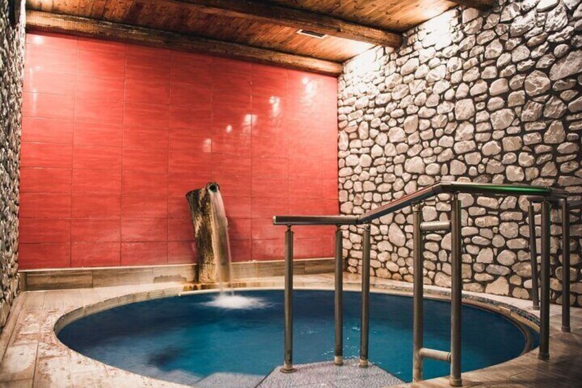 Een jacuzzi met een stenen muur en een rode achtergrond. 5