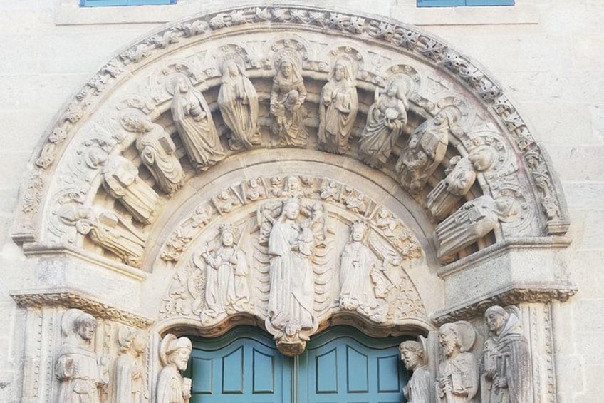 A detailed stone doorway with religious carvings and a blue door. 3