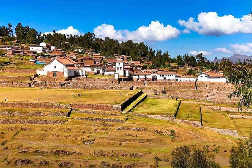 A historical site with ancient ruins, a church, and terraced fields. 2