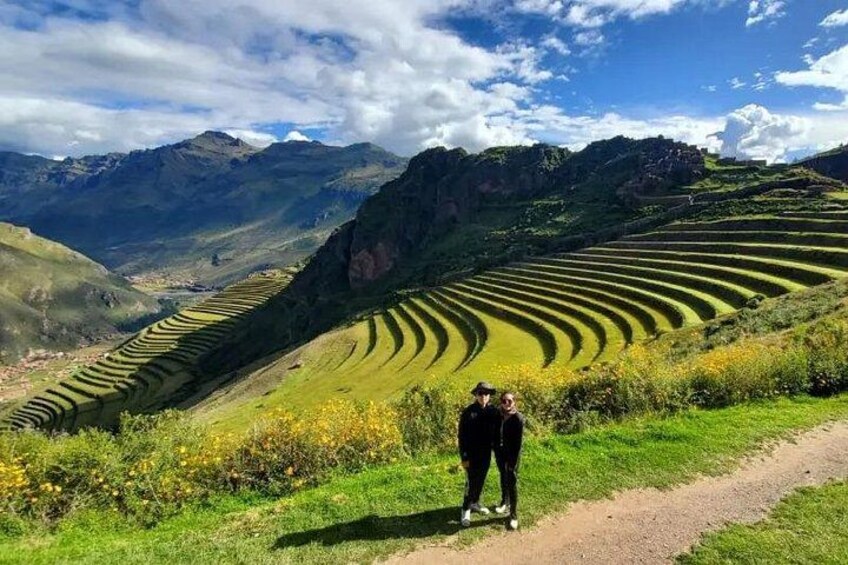 A person standing on a dirt path with terraced fields and mountains in the background. 4