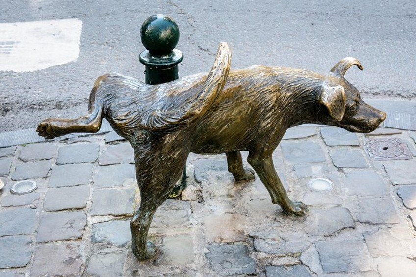 Una estatua de bronce de un perro en un camino adoquinado. 2