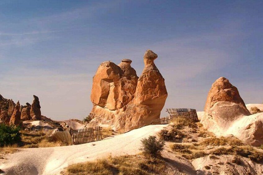 A desert landscape with prominent rock formations and a wooden fence. 4