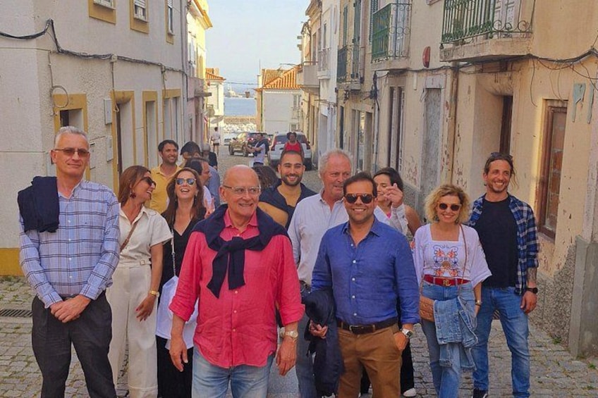 A group of people standing on a cobblestone street in a historic town. 1