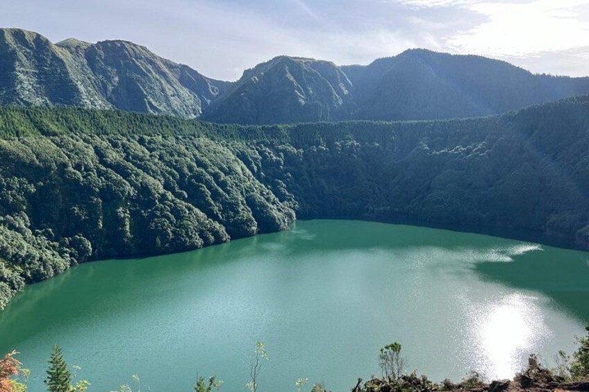 Een groene plas water, omringd door beboste bergen. 5