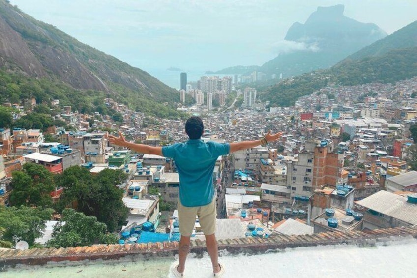 A person standing on a ledge overlooking a city with mountains in the background. 1