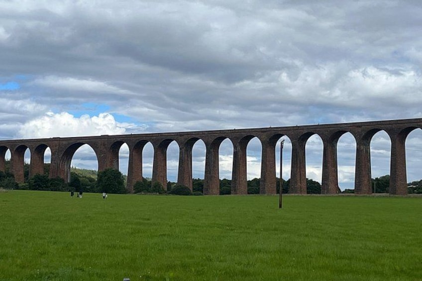 A long brick viaduct with multiple arches spanning a grassy field. 2