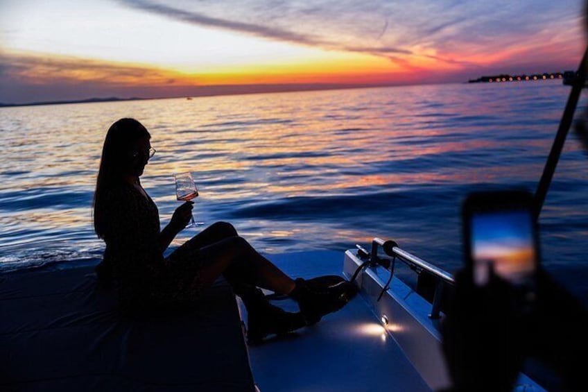 Iemand zit op een boot bij zonsondergang, een glas vasthoudend. 3