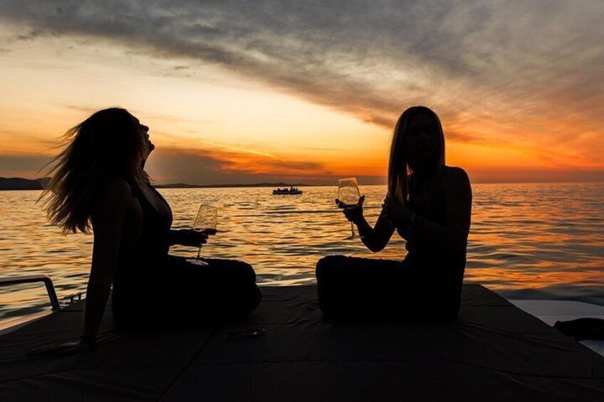 Twee mensen zitten aan het water tijdens de zonsondergang. 2