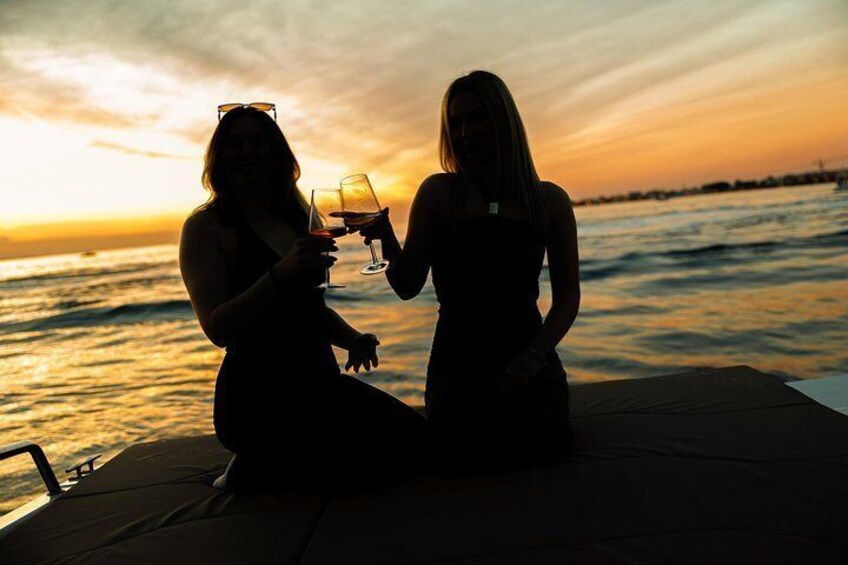 Twee personen proosten met drankjes op een boot bij zonsondergang. 4