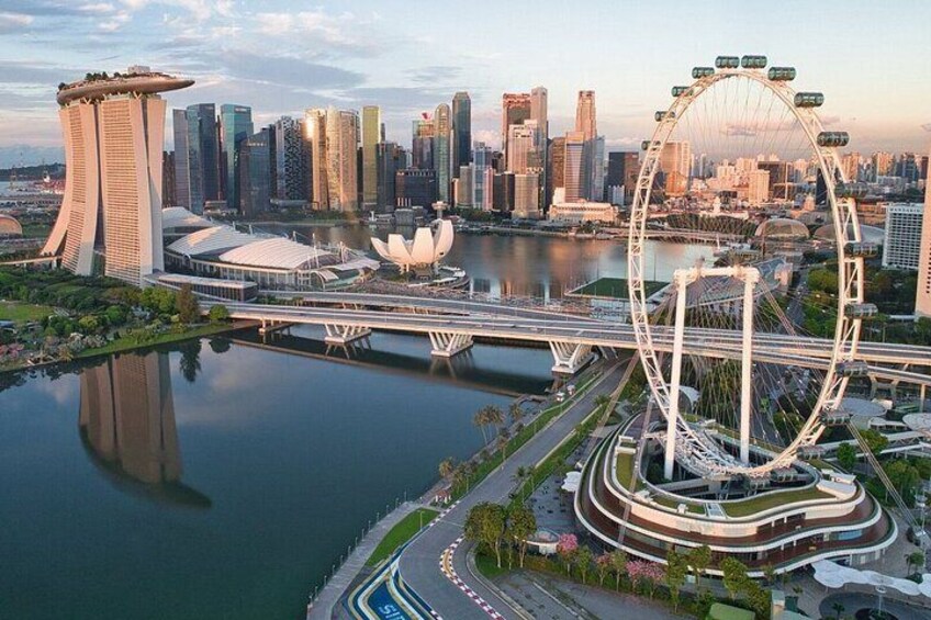 Une vue urbaine avec une grande roue bien visible, un gratte-ciel moderne et un pont enjambant une rivière. 1