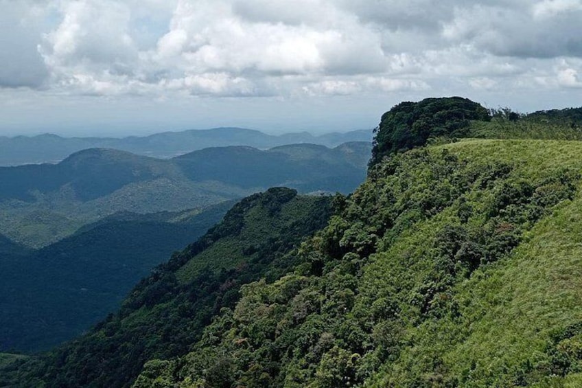 A mountainous landscape with dense green vegetation and a cloudy sky. 4