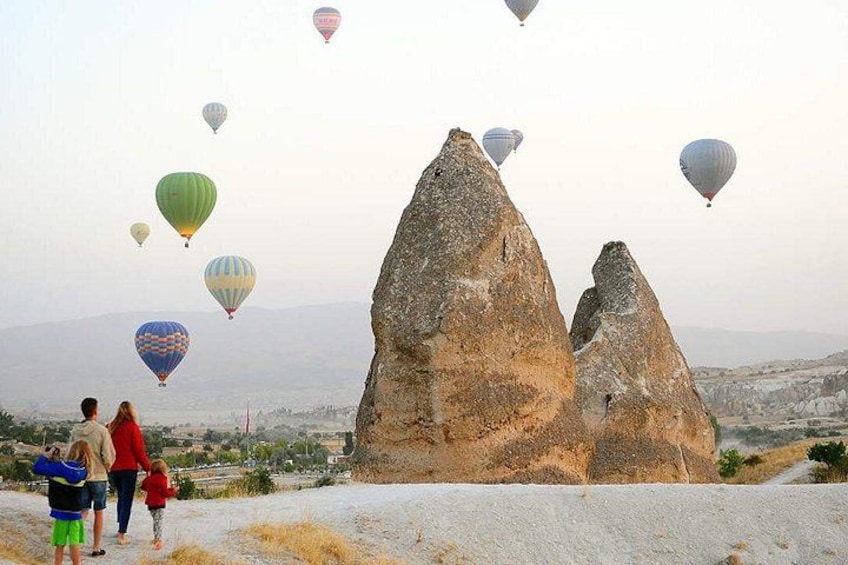 A landscape with large rock formations and hot air balloons in the sky. 4
