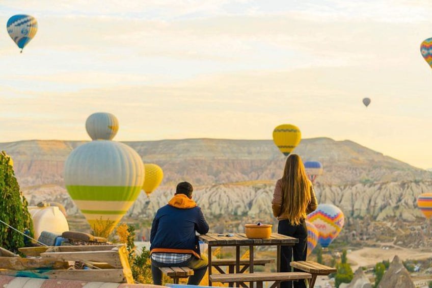 People sitting at a table with hot air balloons in the background. 3
