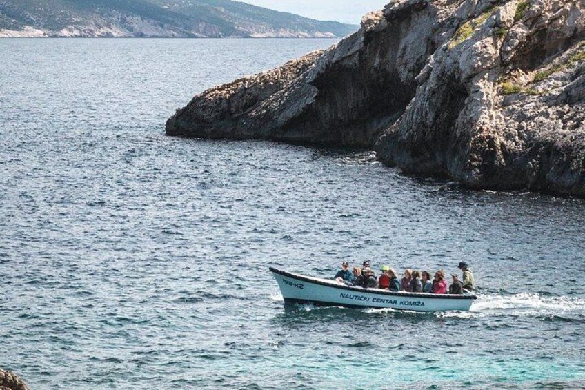 A boat with passengers on a calm sea near rocky cliffs. 3