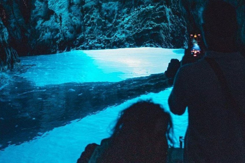 A person in a cave with a flashlight, ice formations, and a river. 1