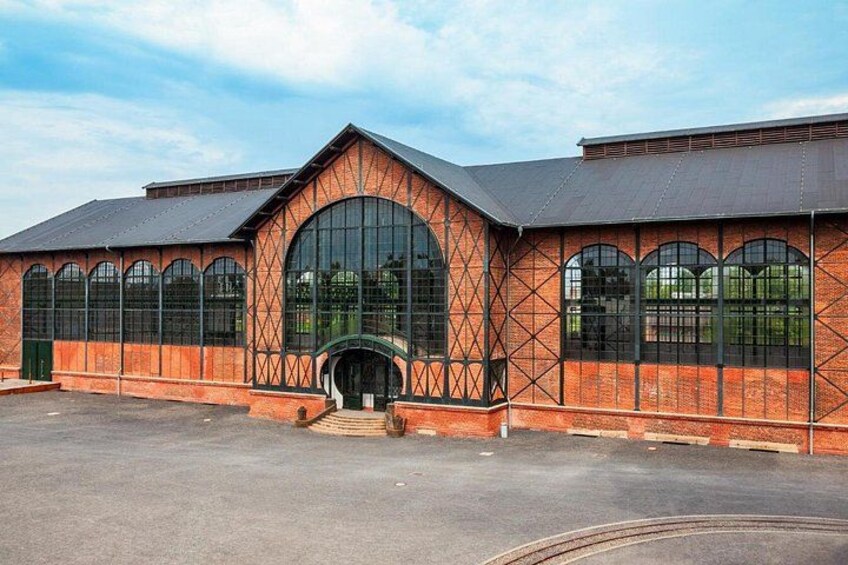 A large brick building with arched windows and a central archway. 5