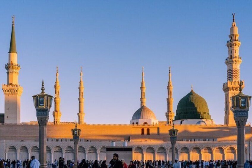 A mosque with multiple minarets and domes, surrounded by a crowd of people. 4