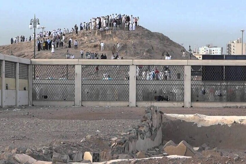 A large crowd on a hill with a fenced area in the foreground. 2