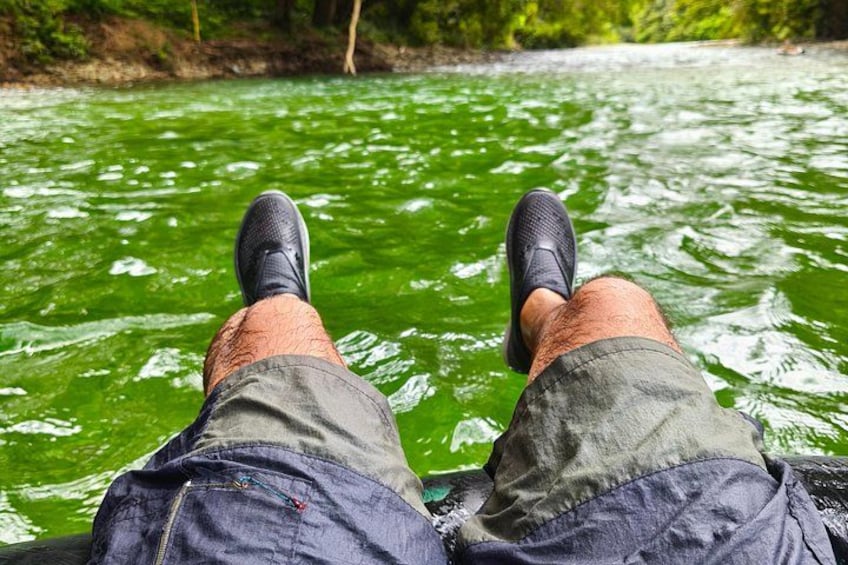 Una persona sentada con las piernas cruzadas en un bote sobre un río verde. 1