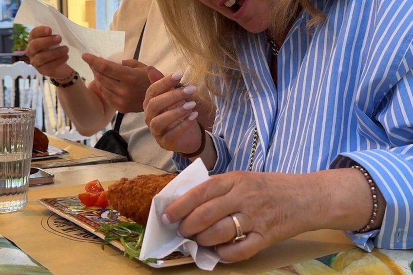 Una persona comiendo un sándwich, con una servilleta, un vaso de agua y un plato de verduras. 1