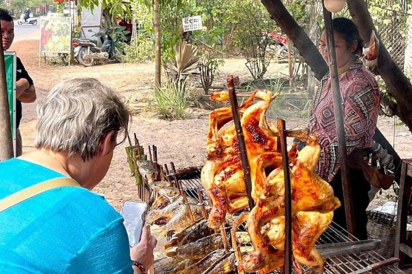 Eine Person grillt Hähnchen im Freien am Spieß. 1