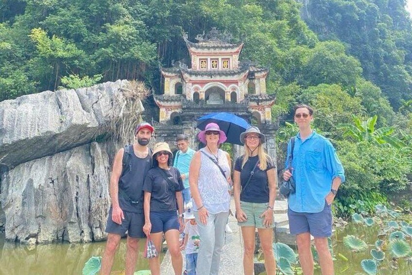 Un grupo de personas frente a un templo tradicional, con una formación rocosa a la izquierda. 4