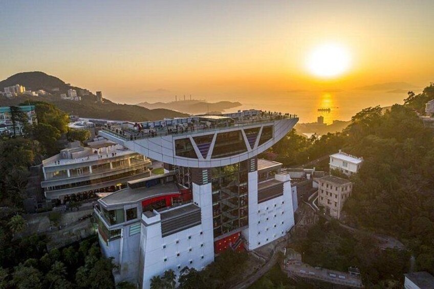 A modern building with a unique curved roof, surrounded by greenery and overlooking a body of water during sunset. 3