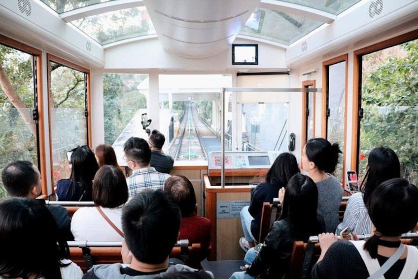 A group of people seated inside a train car, looking out at a railway track. 5