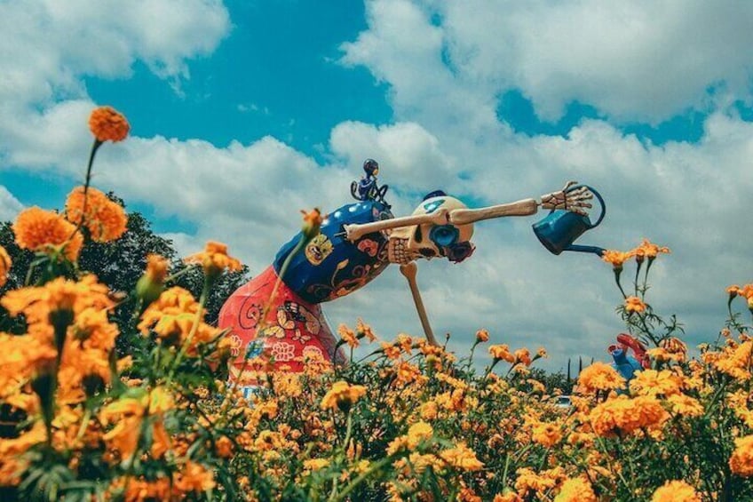 Una scultura raffigura una figura che annaffia fiori in un campo. 1