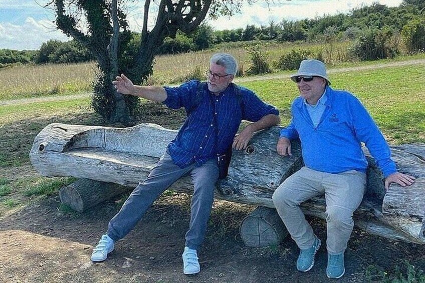 Two men sitting on a log bench in a park. 3