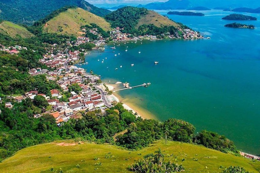 A coastal town with a pier, surrounded by lush green hills and clear blue waters. 5