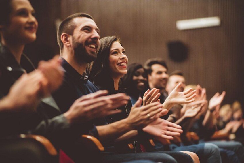People seated in an auditorium clapping. 4