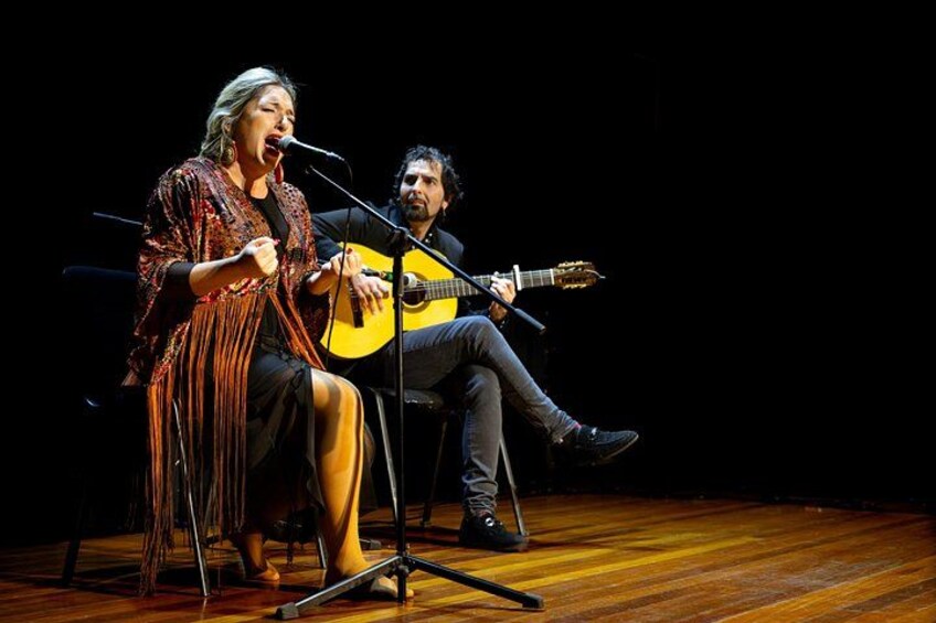 Two people performing music on stage with a guitar and microphone. 3