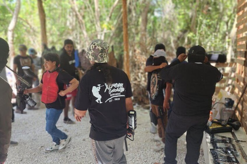 Un grupo de personas en una zona boscosa, algunas con gorros de camuflaje y otras con ropa informal. 2