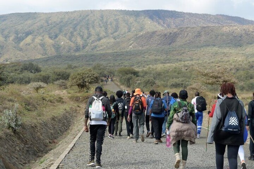 Un gruppo di escursionisti che cammina su un sentiero sterrato, con un paesaggio montuoso sullo sfondo. 1