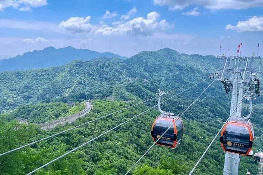 A cable car system with two gondolas against a backdrop of lush green mountains. 4