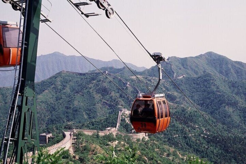 A cable car in a mountainous area with lush greenery and a winding road below. 2