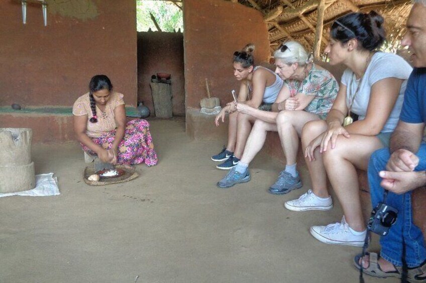 Un grupo de personas sentadas en el suelo en un entorno rústico, posiblemente participando en una actividad o conversación tradicional. 5