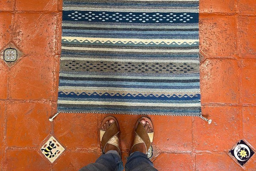A patterned rug on a tiled floor with a person's feet standing on it. 3