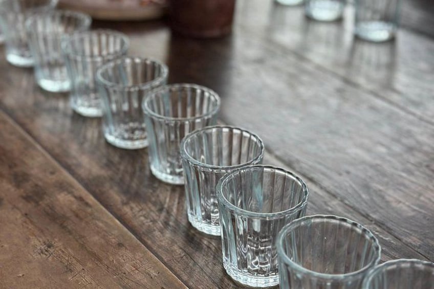 A row of empty glass shot glasses on a wooden table. 4