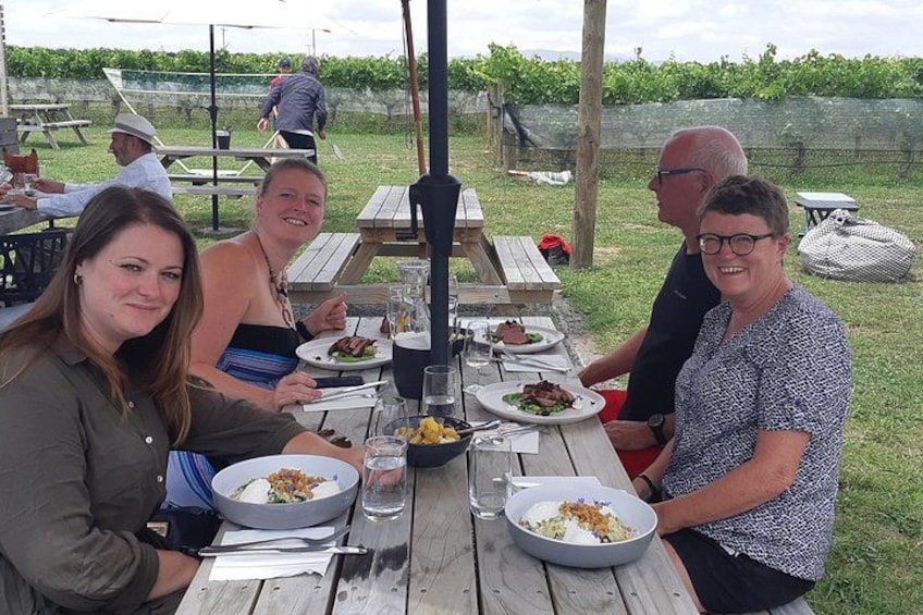 Un groupe de personnes est réuni autour d’une table de pique-nique en plein air et déguste différents plats. 1
