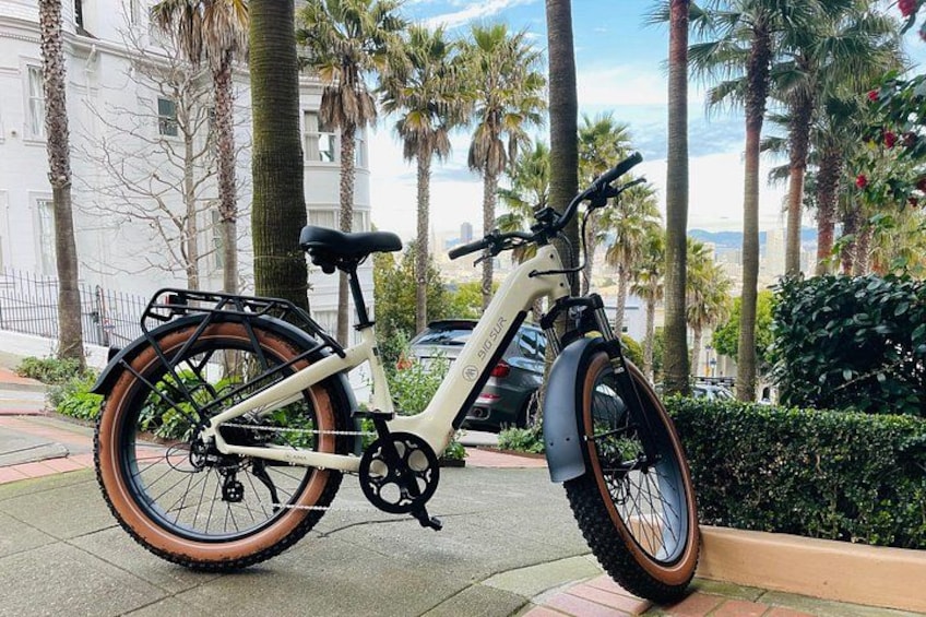En vit elcykel med svart sadel och bruna däck står parkerad på en trottoar. 2