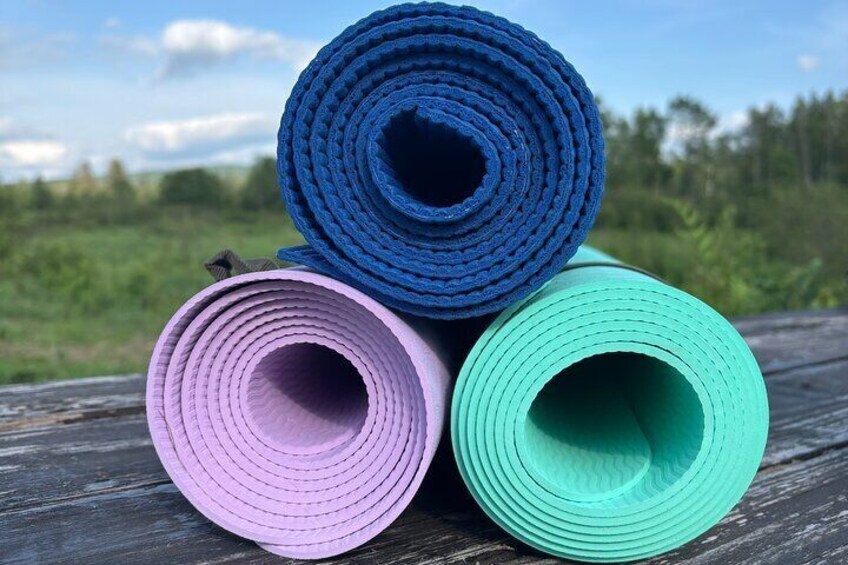 Tre yogamåtter i blå, lyserød og grøn farve på en træoverflade. 4