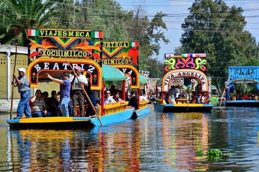 Colorful boats with passengers, water, and trees in the background. 4